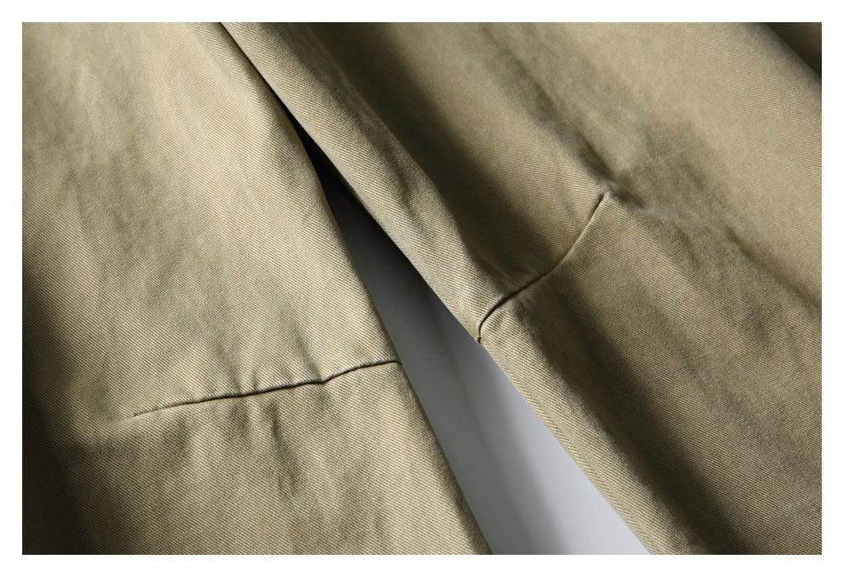 Close-up of khaki trouser legs with stitched panel seams and a faded finish.