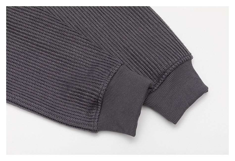Close-up of charcoal-gray textured knit sleeves ending in wide ribbed cuffs.