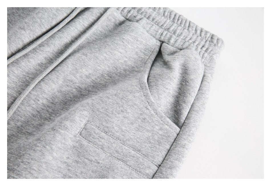Close-up of light gray heather sweatpants showing the elastic waistband and a side pocket.