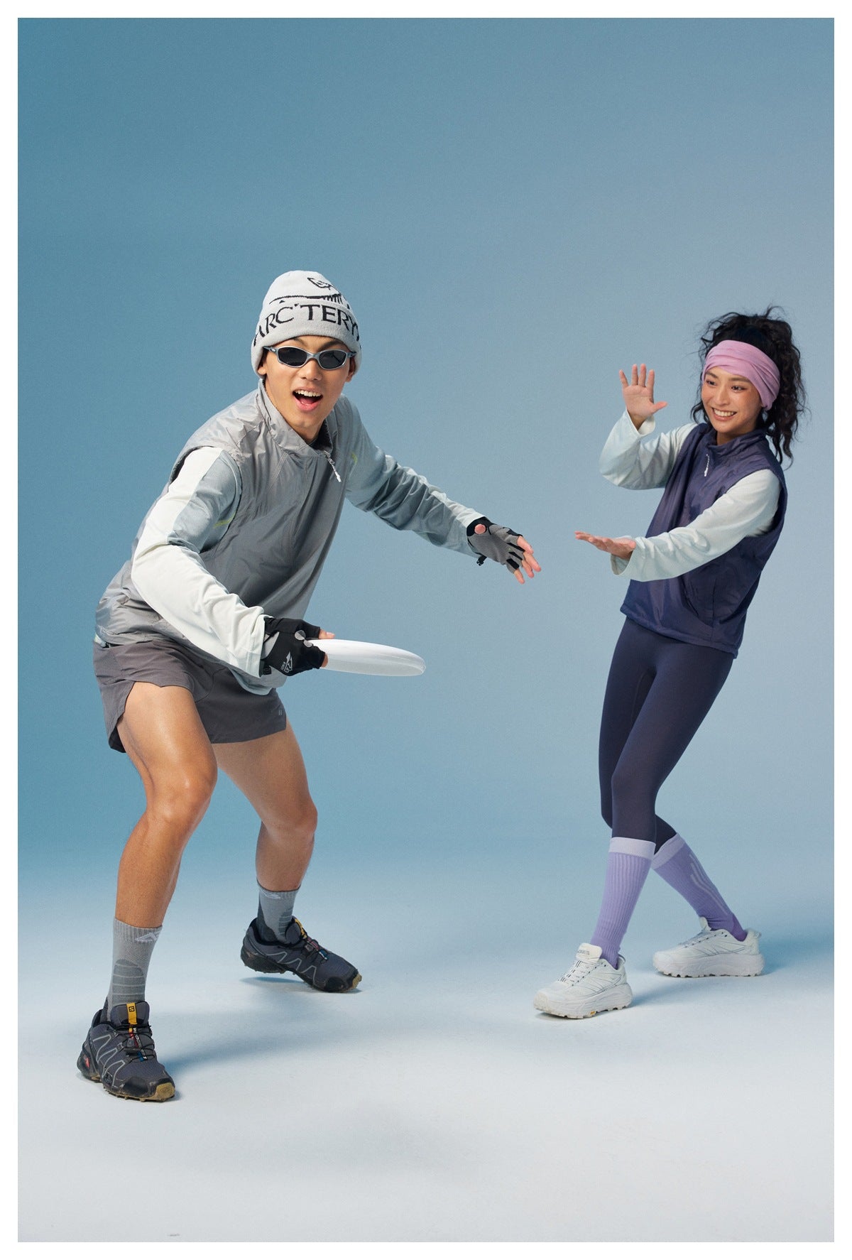 Two models in gray and purple sleeveless vests pose with a flying disc.