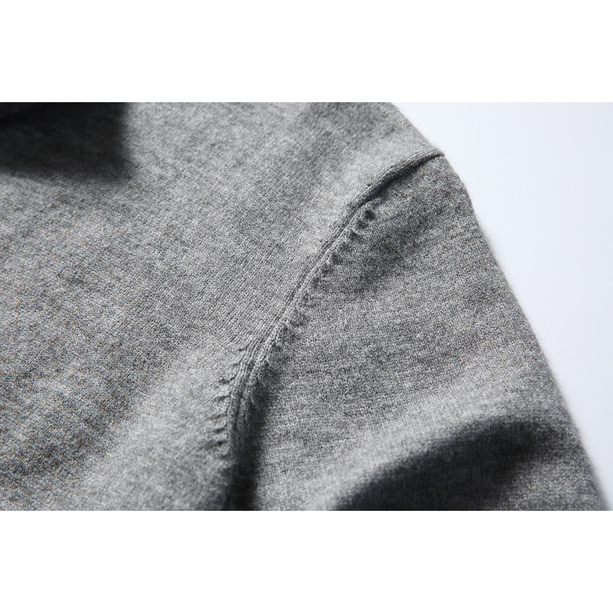 Close-up of a curved seam on gray knit fabric.