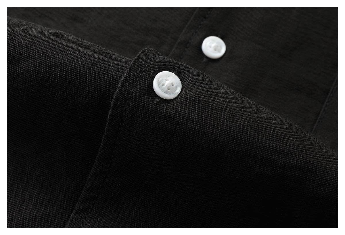 Close-up of white buttons and a cuff on a black shirt.