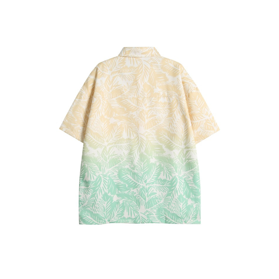 Back view of a short-sleeve shirt with a pale yellow-to-mint gradient and white tropical leaf print.