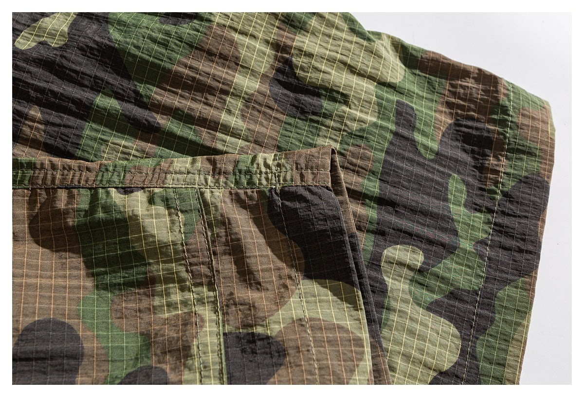 Close-up of camouflage shorts showing a stitched pocket edge and garment seams.