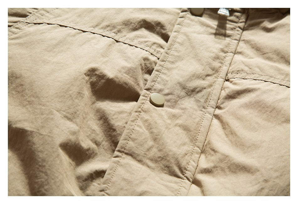 Close-up of tan jacket fabric and front placket with a snap button and stitched seams.