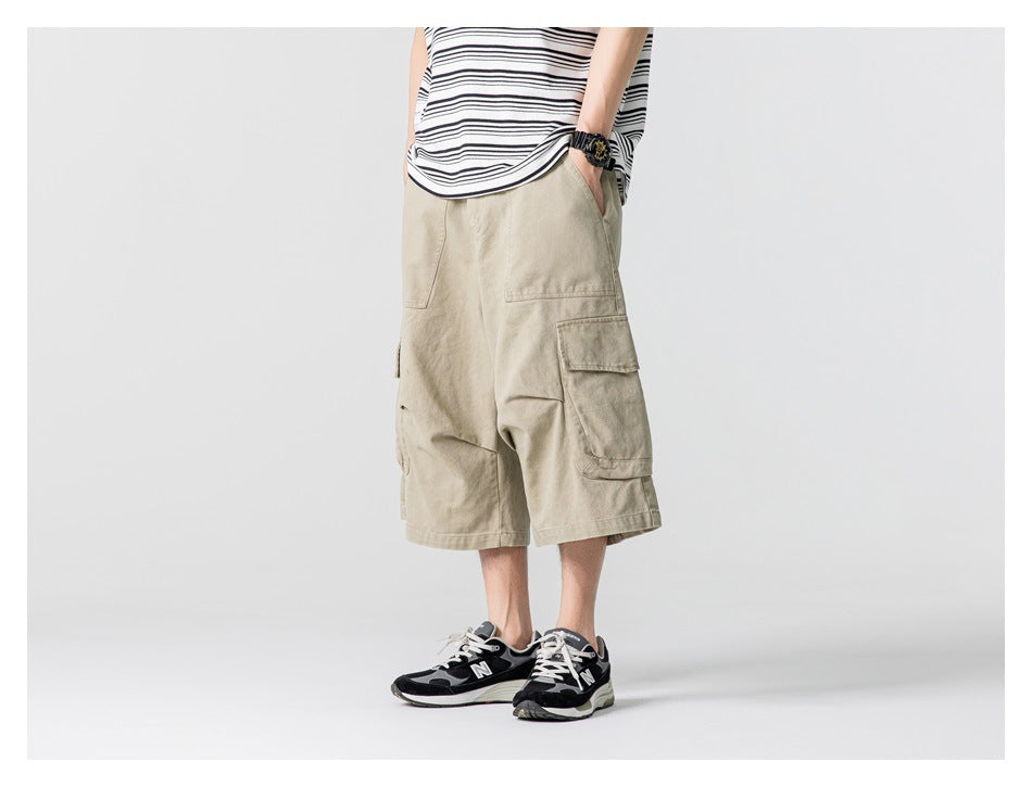 Model wearing loose beige cargo shorts with flap cargo pockets, shown from a front-side angle.