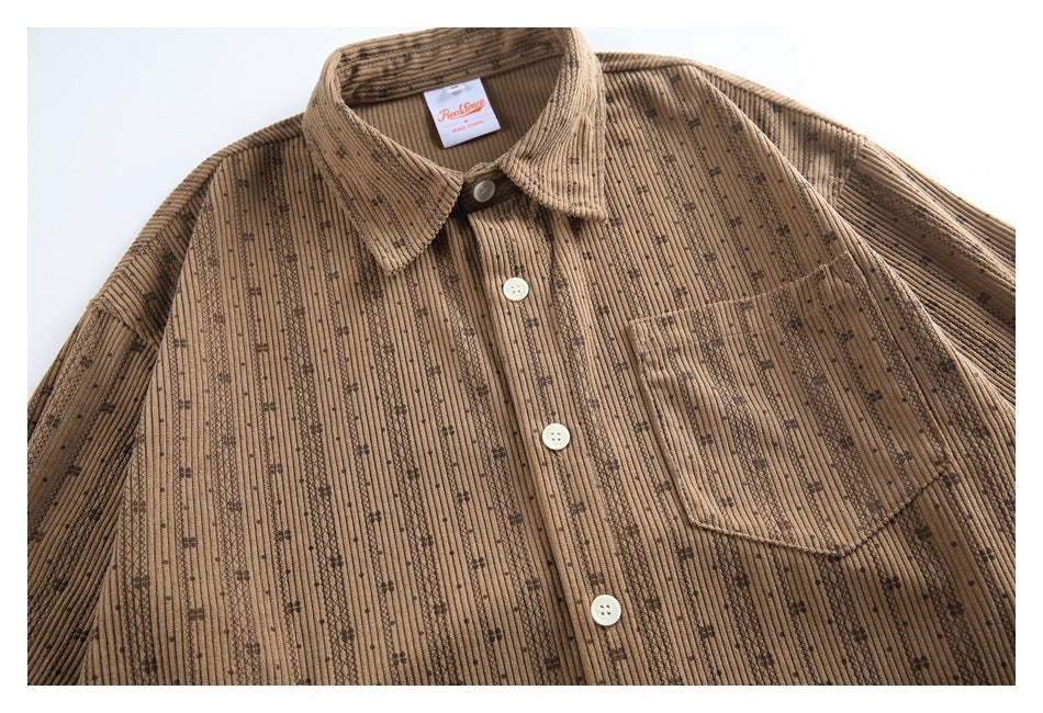 Close view of a tan button-up shirt with a pointed collar, chest pocket, and dark vertical patterned stripes.