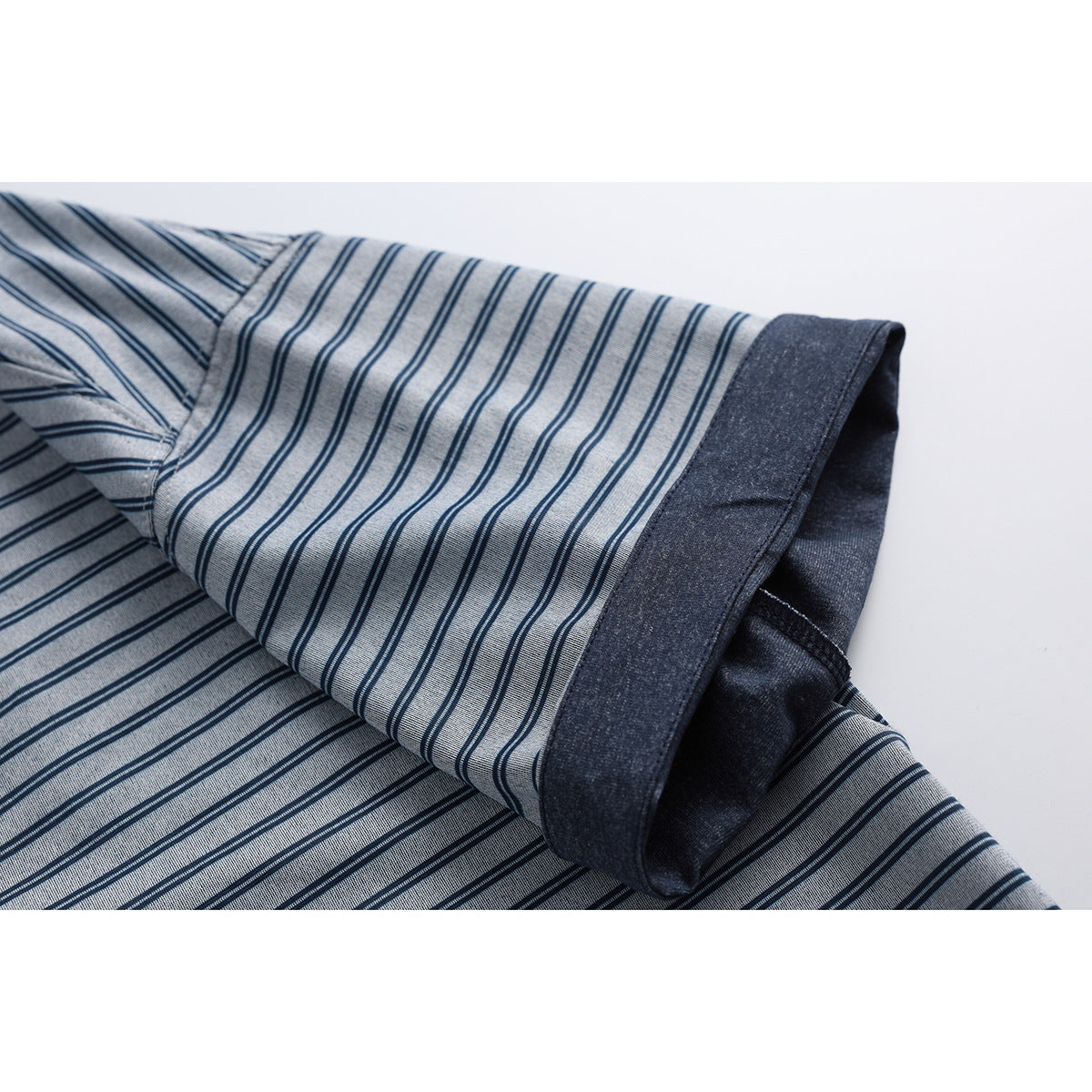 Close-up of a short sleeve on a blue-gray striped shirt, showing the dark contrasting cuff and reverse.