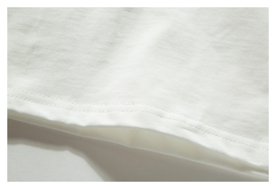 Close-up of the stitched bottom hem on an off-white T-shirt.