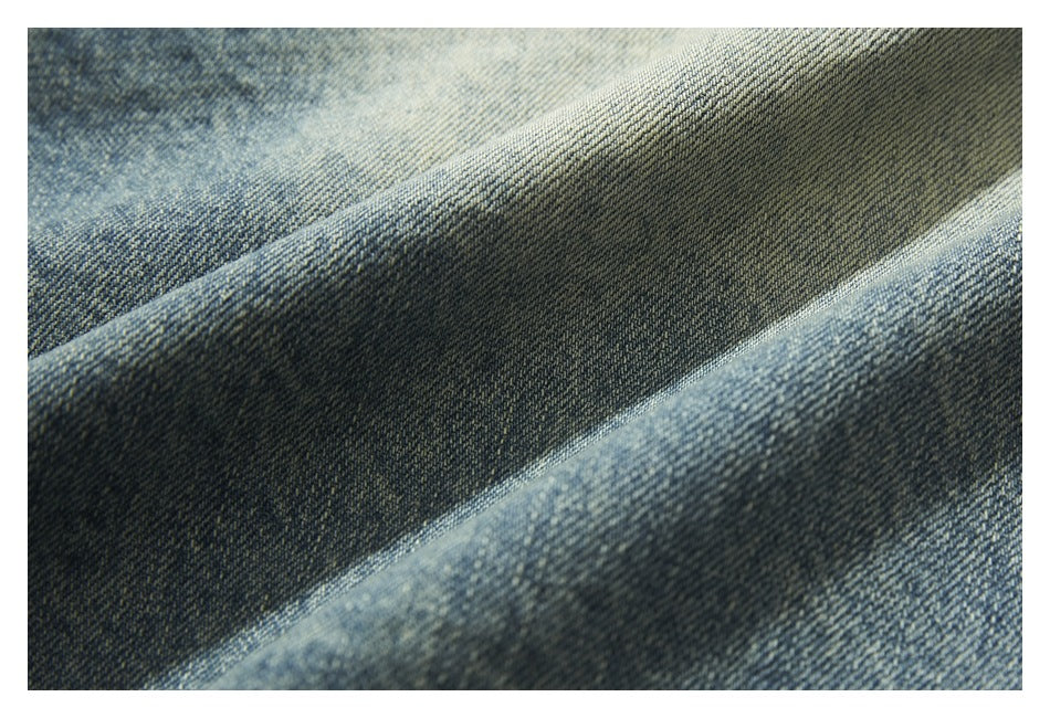 Macro view of blue denim fabric folded into ridges, showing its woven texture.