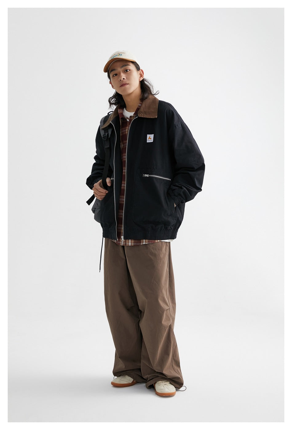 Full-length view of a model wearing a black jacket with a brown collar, zip pockets and elastic cuffs and hem.