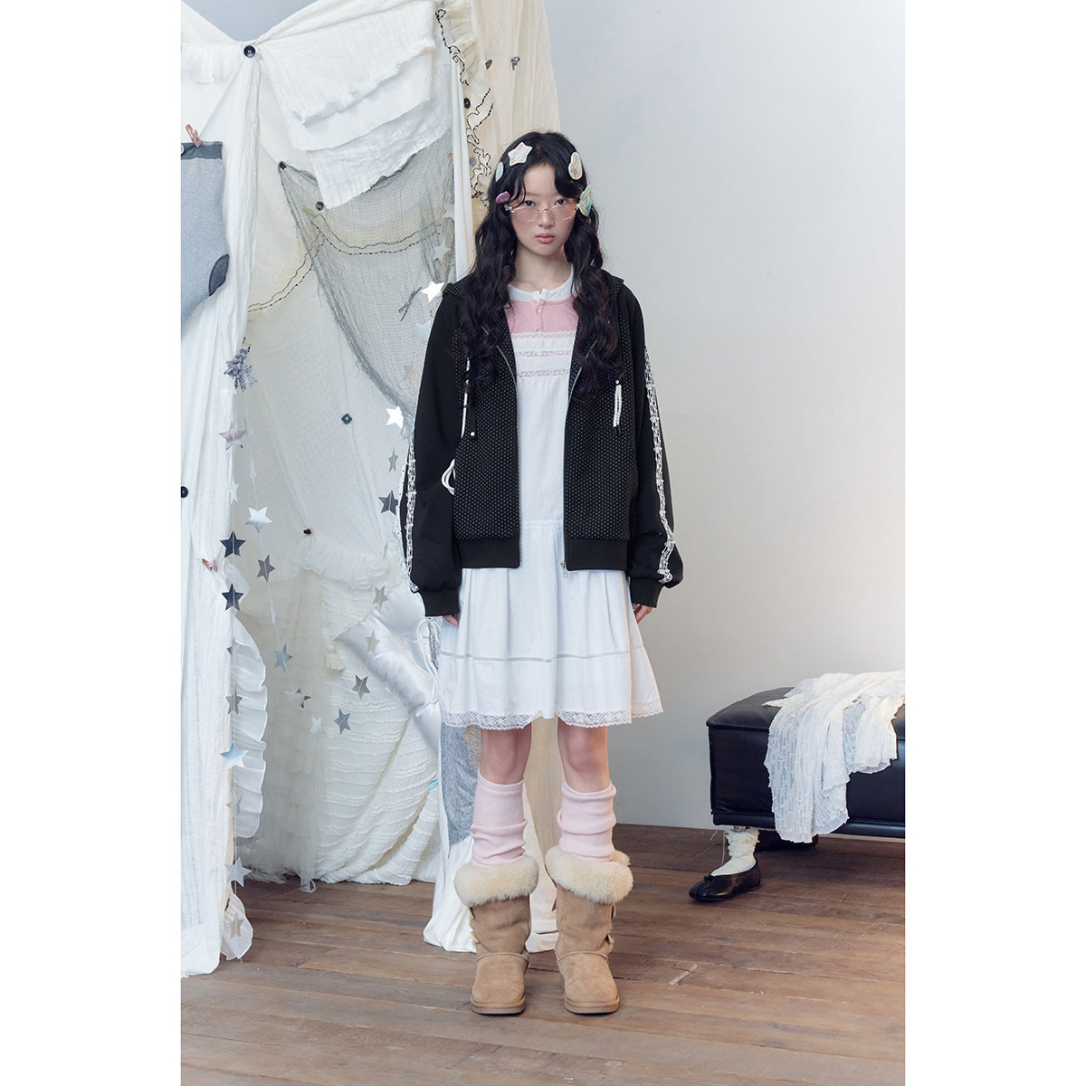 Full-length model wearing a black dotted zip hoodie with white sleeve trim over a white and pink dress.