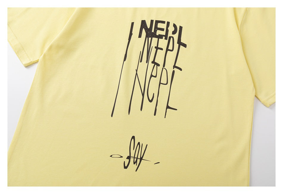 Cropped view of a pale yellow T-shirt front with oversized black stylized lettering and a small signature graphic.