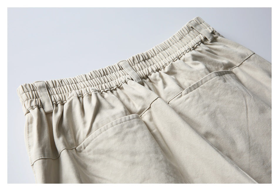 Cropped back view of light beige trousers showing an elastic waistband and two patch pockets.