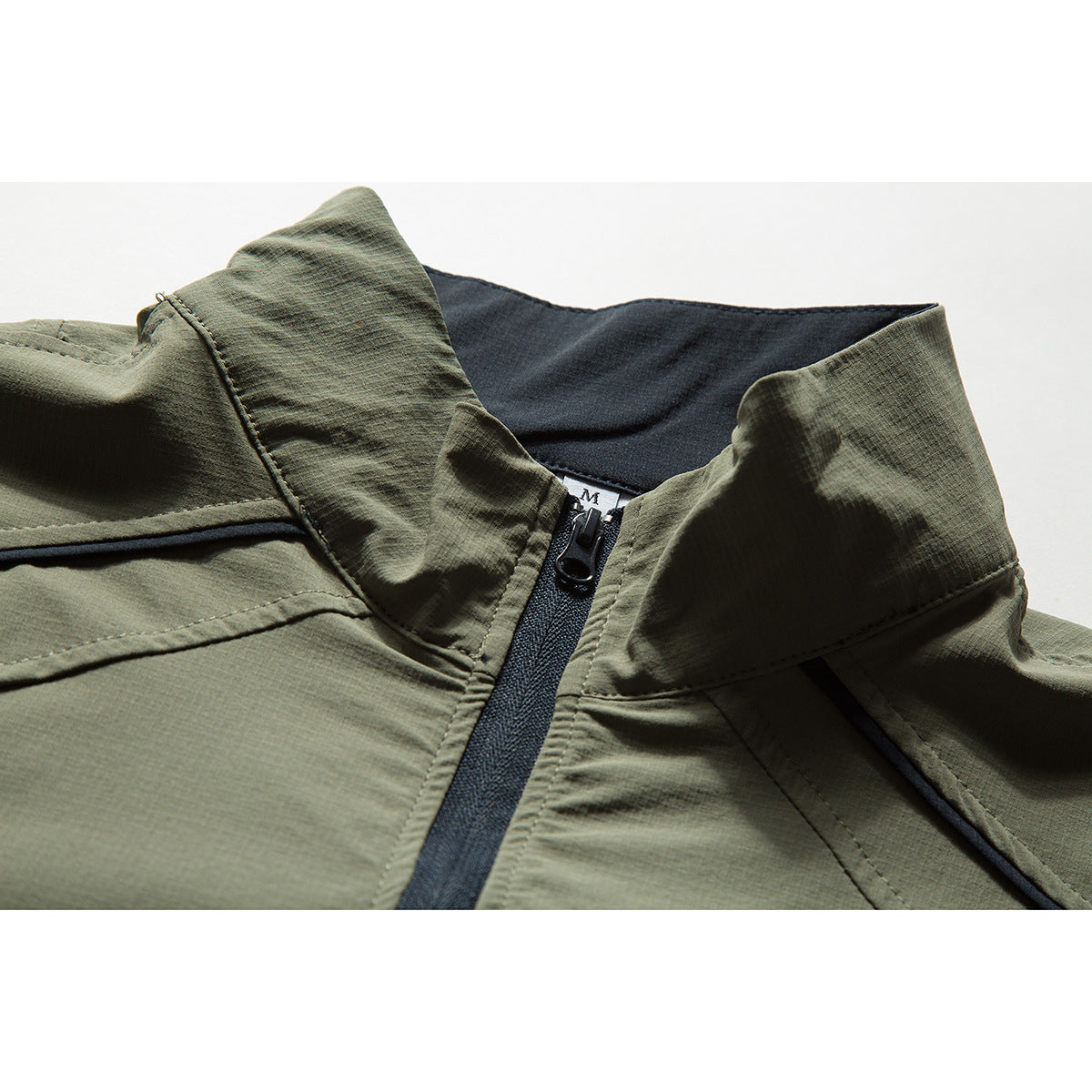 Close-up of an olive short-sleeve pullover's raised collar, black quarter zipper, and dark inner collar.