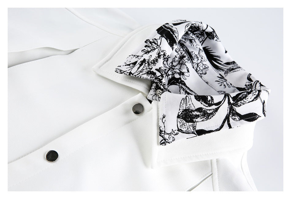 Close-up of a white garment collar with black floral-patterned lining and dark snap buttons.