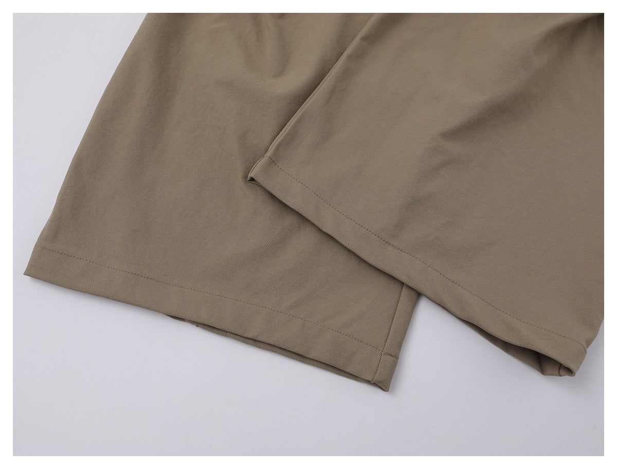 Close-up of two taupe trouser leg hems with visible stitching.