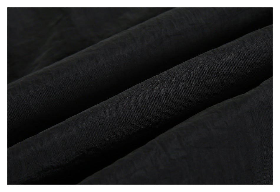 Close-up showing the softly creased, dark black fabric surface.