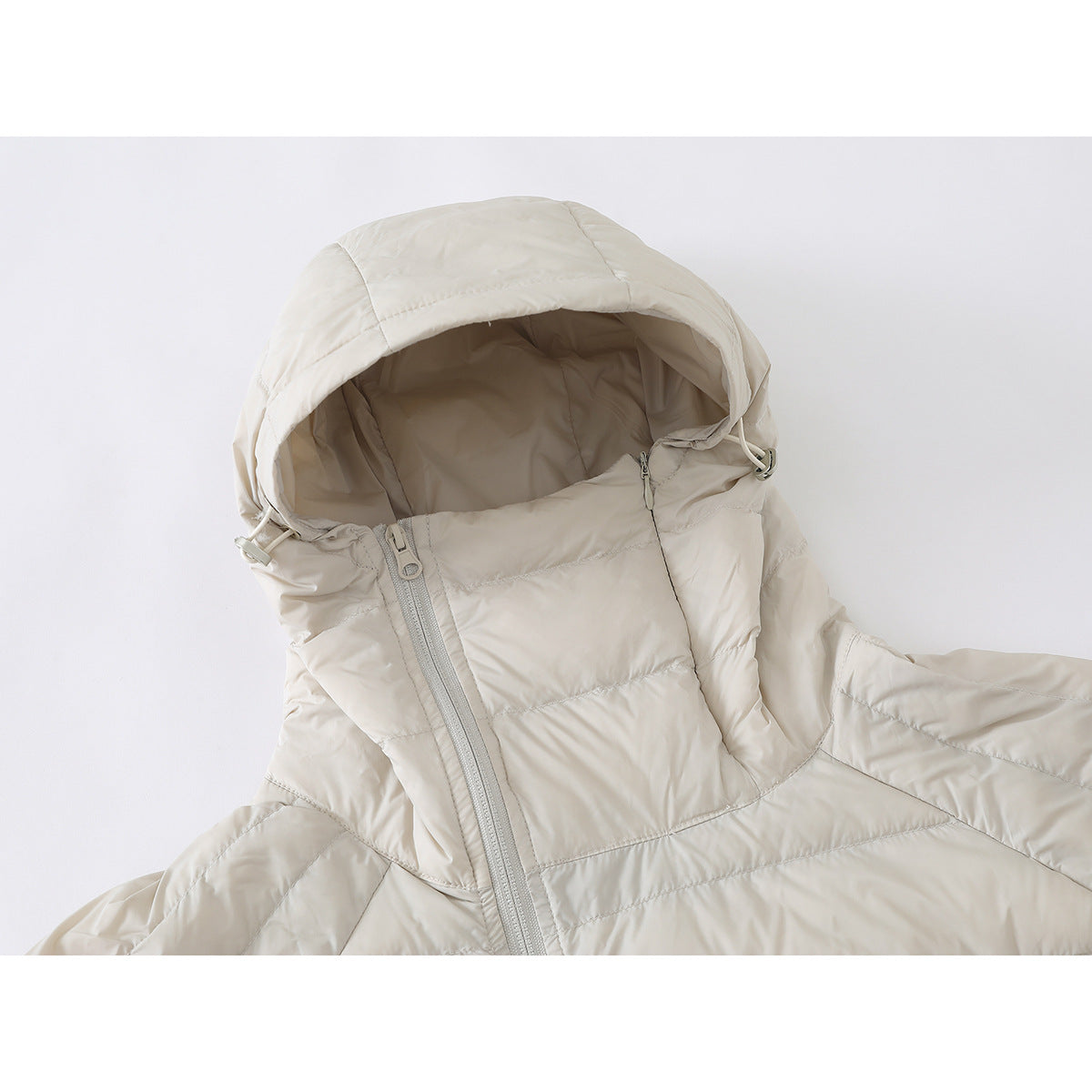Close-up of an ivory quilted jacket showing its oversized adjustable hood and diagonal front zipper.
