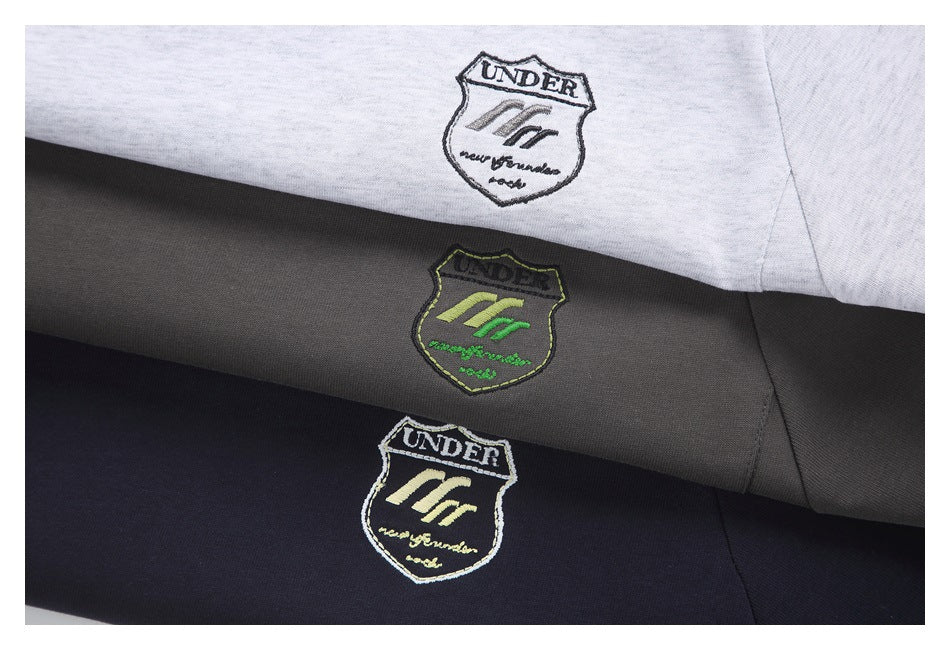 Close-up of white, charcoal gray, and black garments with embroidered shield-shaped chest emblems.