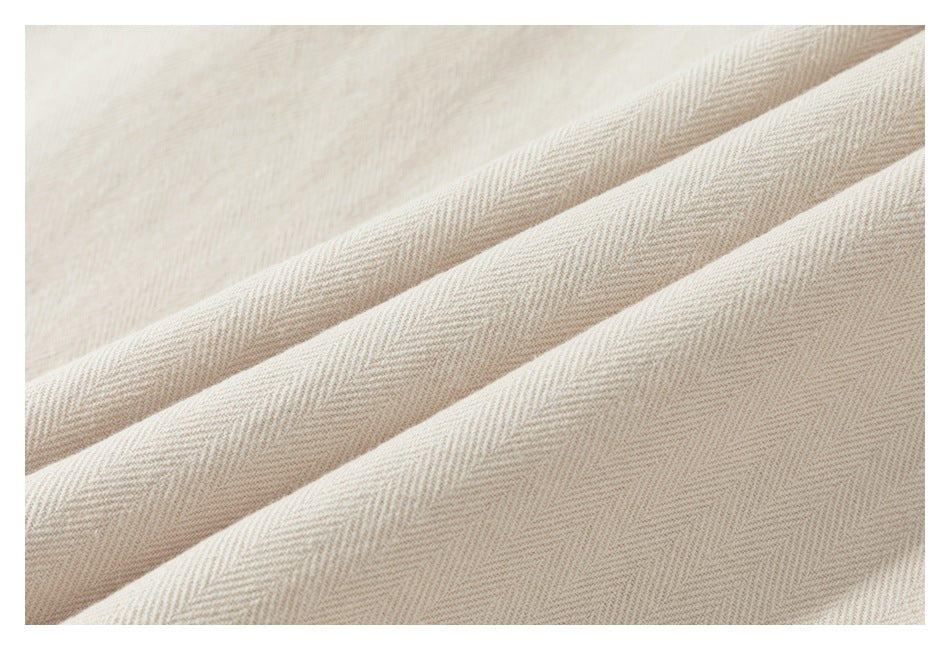 Close-up of folded cream fabric showing a subtle herringbone weave.