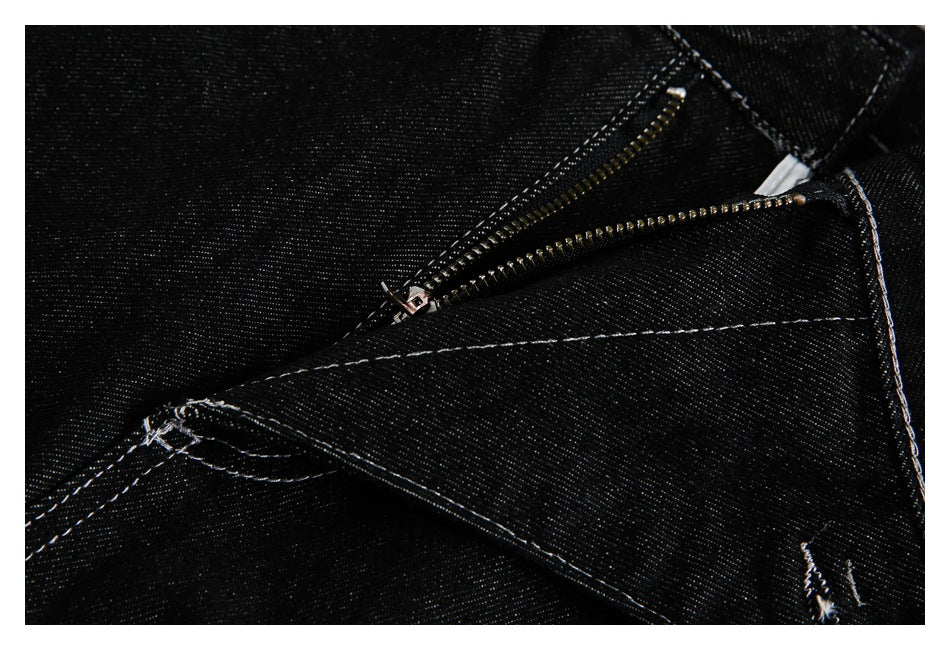 Close-up of black jeans with the zipper fly partly open and white contrast stitching.