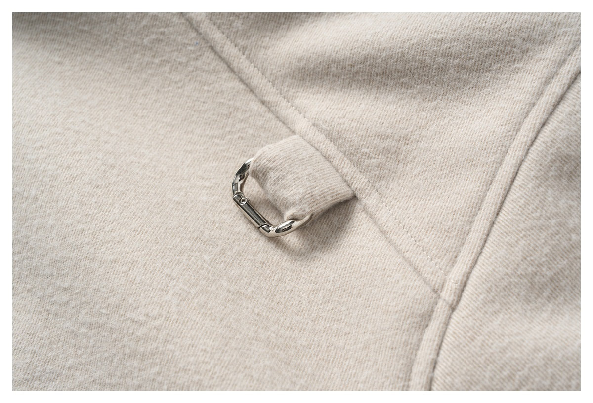 Close-up of beige heathered fabric with a small silver metal ring fastening.