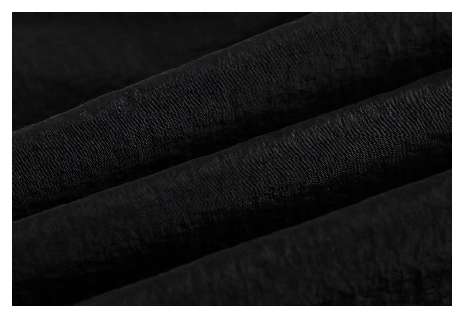 Close-up of black fabric arranged in diagonal folds, showing its subtle woven texture.