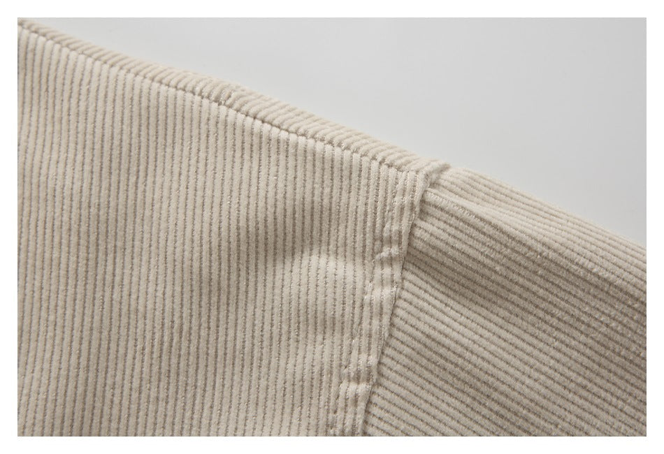 Close-up of cream corduroy fabric and a stitched shoulder seam.