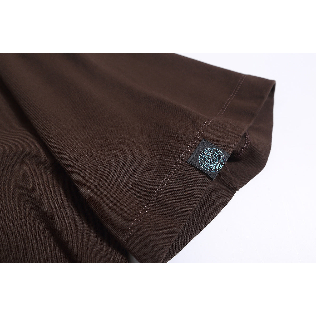 Close-up of a dark brown T-shirt sleeve and hem with a small attached woven label.