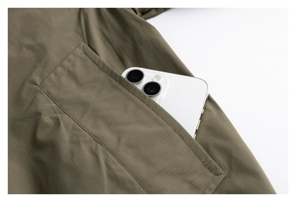 Close-up of an olive jacket’s angled pocket holding a white smartphone.