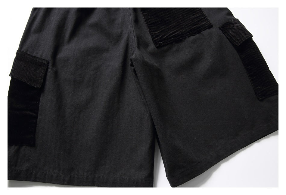 Cropped front view of black shorts laid flat, with large pockets and ribbed black trim.
