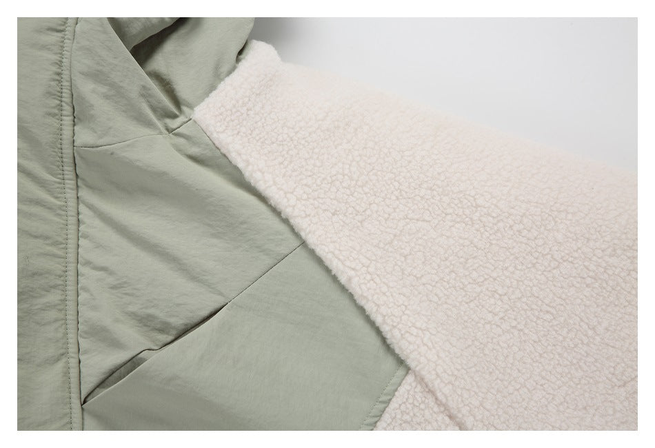 Close-up of the jacket's sage-green panels and cream fleece sleeve, showing seam construction.