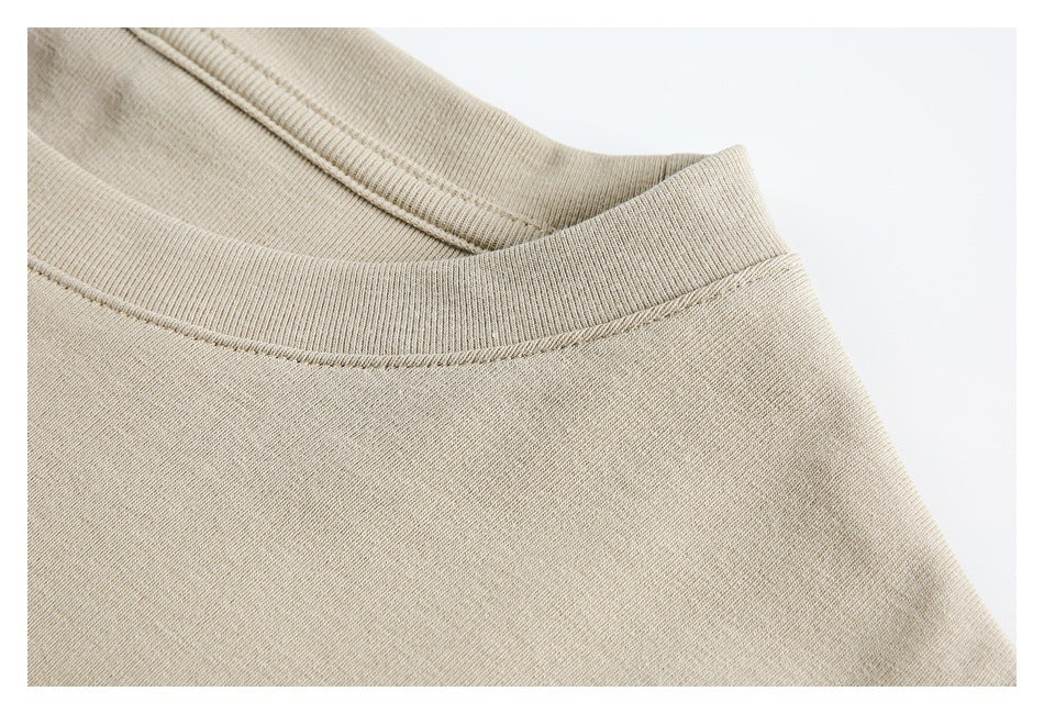Close-up of a beige ribbed crew collar and shoulder seam with visible stitching.