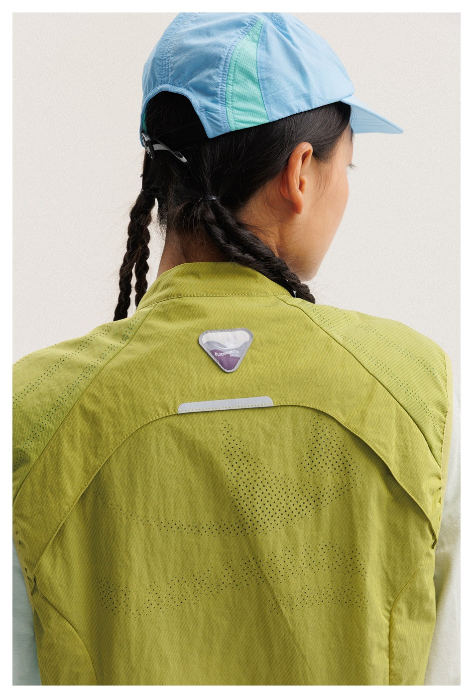 Close-up of the lime-green vest back, showing perforated panels and a reflective detail below the collar.