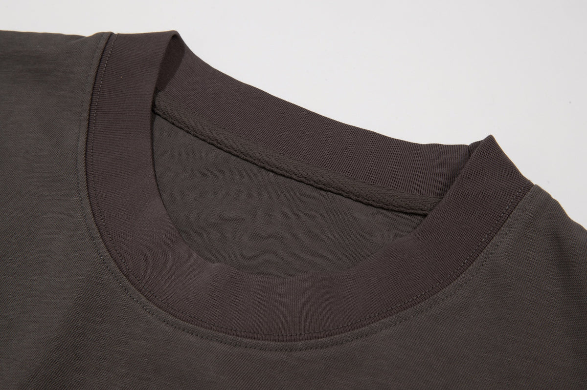 Close-up of a dark brown crew-neck shirt showing its ribbed collar, neckline stitching, and fabric.