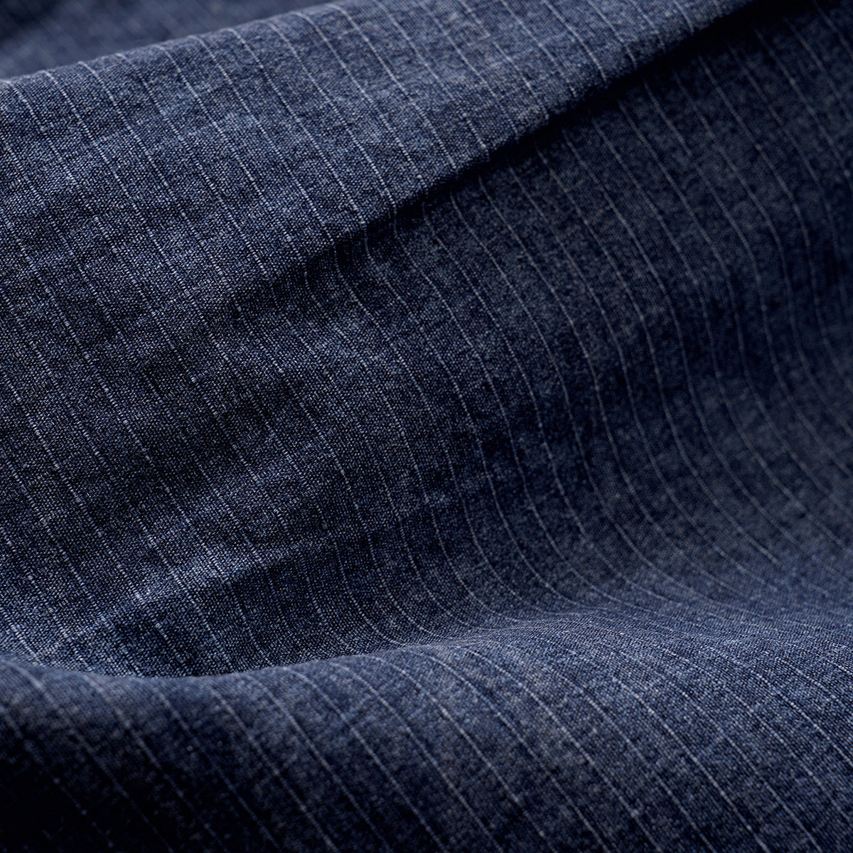 Close-up of blue fabric with a fine, subtle grid pattern and soft folds.