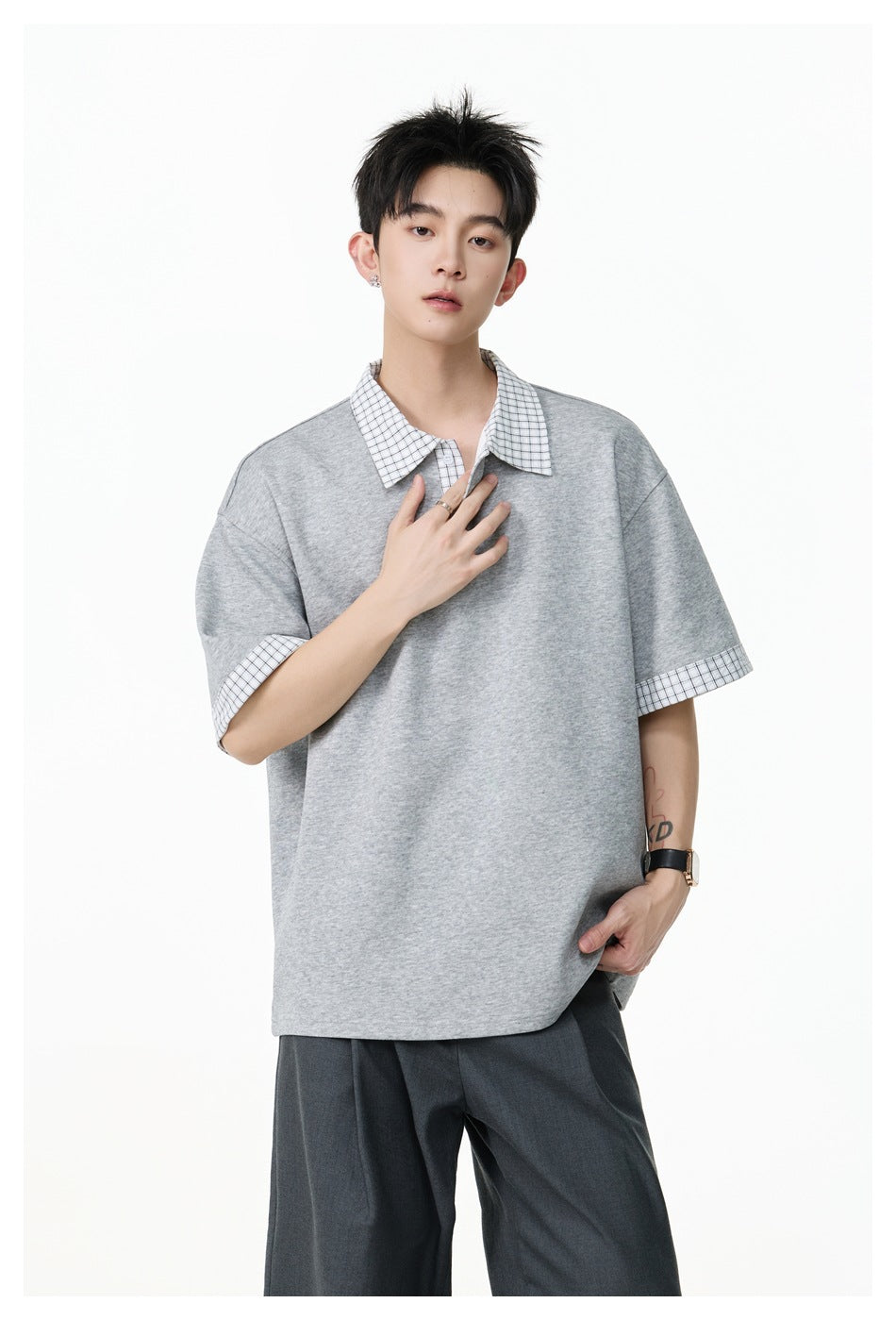 Front view of a model wearing an oversized heather-gray polo with a checked collar and sleeve cuffs.