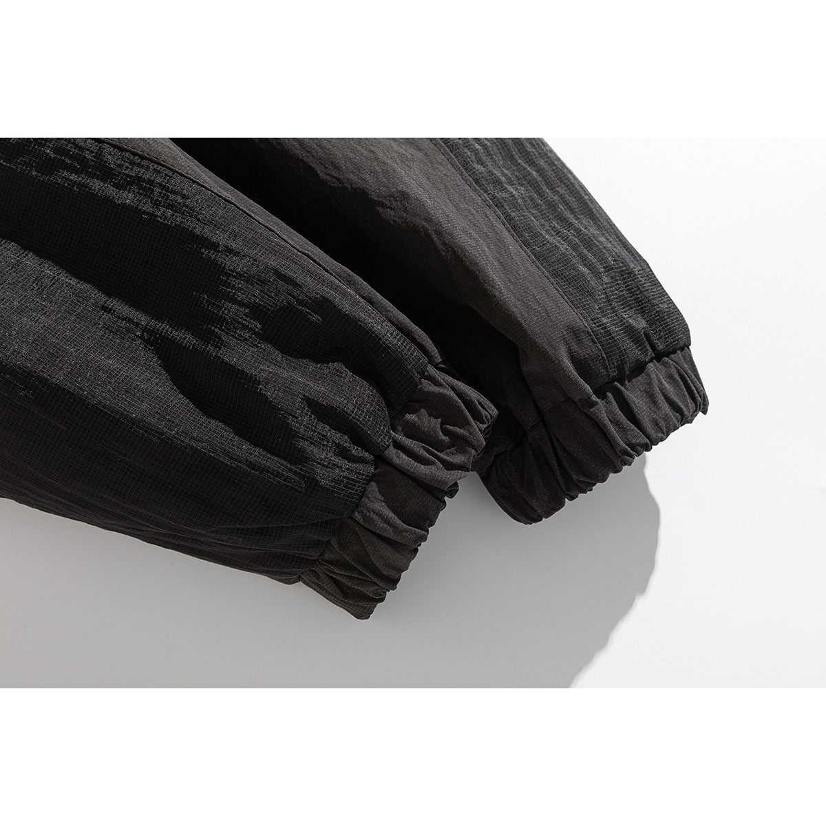 Close-up of the black jacket's sleeves ending in gathered elastic cuffs, with textured panels.