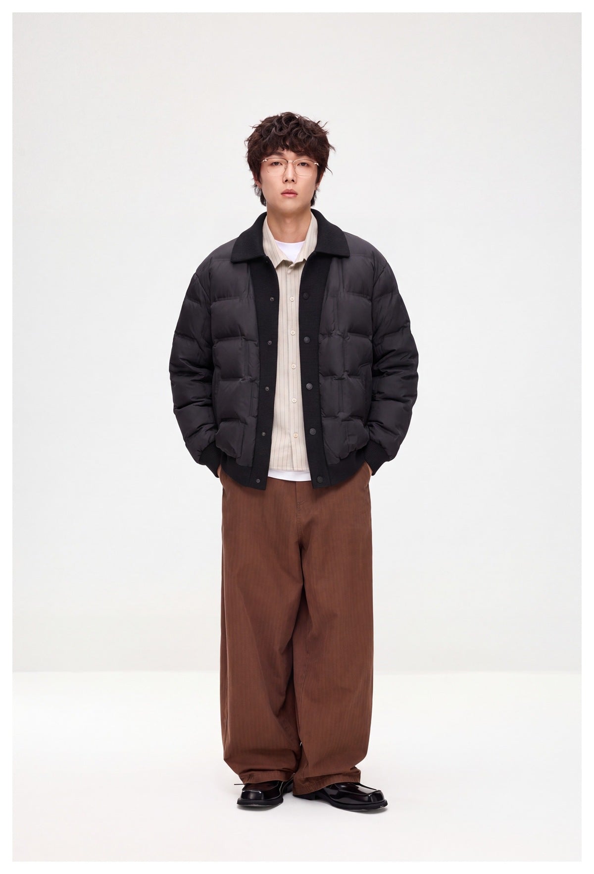 Full-length model wearing a dark quilted jacket with a ribbed black collar, button placket, cuffs and hem.