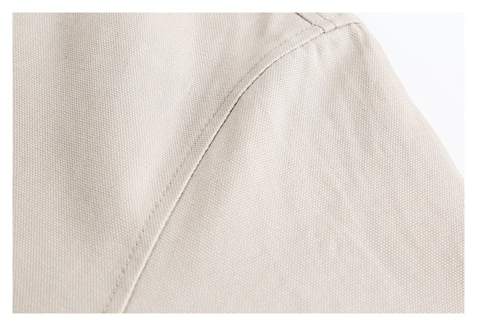 Close-up of beige woven garment fabric with a curved stitched seam.