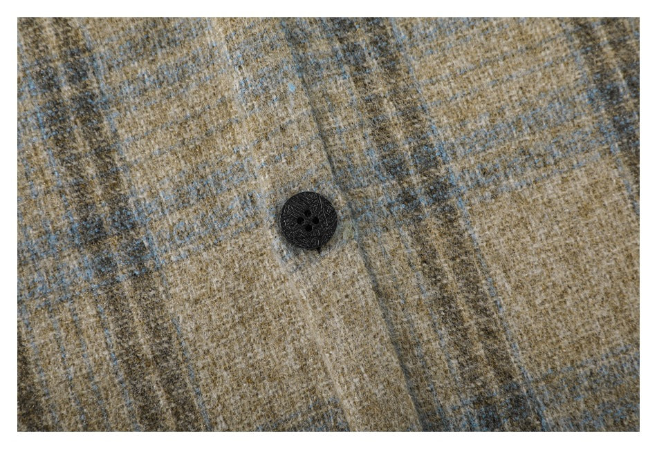 Macro view of a black four-hole button on the tan and gray plaid shirt.