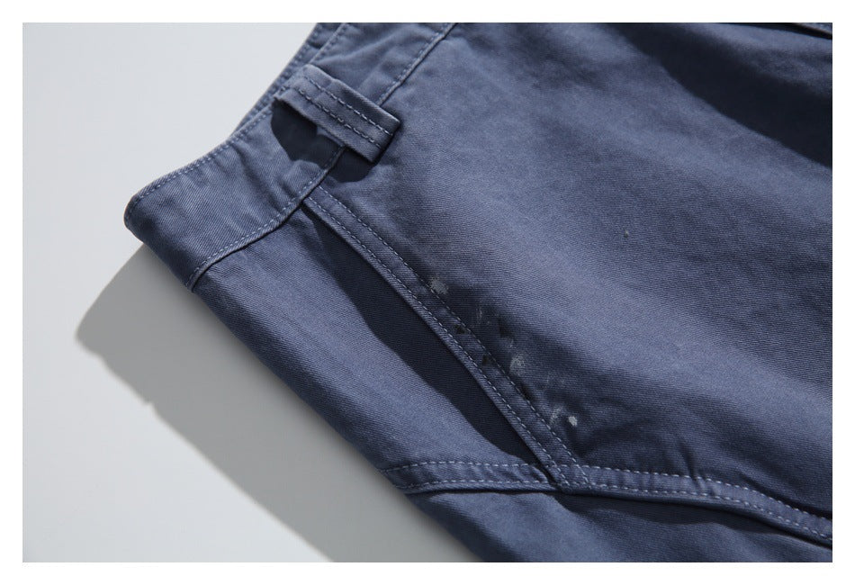 Close-up of the waistband and curved side seam on blue-gray pants, with subtle worn marks.