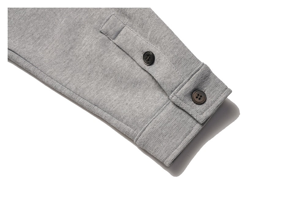 Close-up of a gray garment sleeve cuff with two dark buttons.