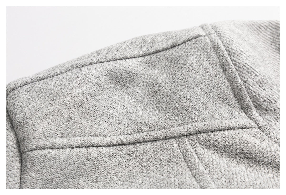 Close-up of a gray coat's textured fabric and stitched shoulder seam.