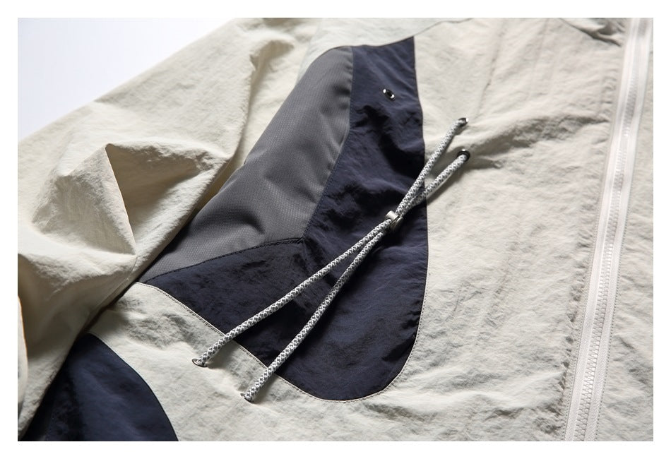 Close-up of a jacket's navy and gray front panel, with adjustable cords and a metal eyelet.