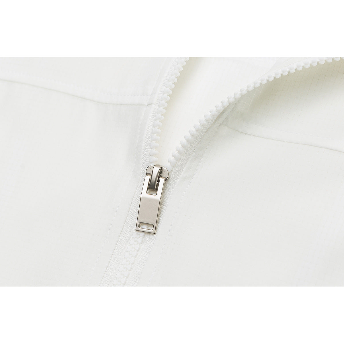Close-up of the white jacket's chunky front zipper and rectangular metal pull.