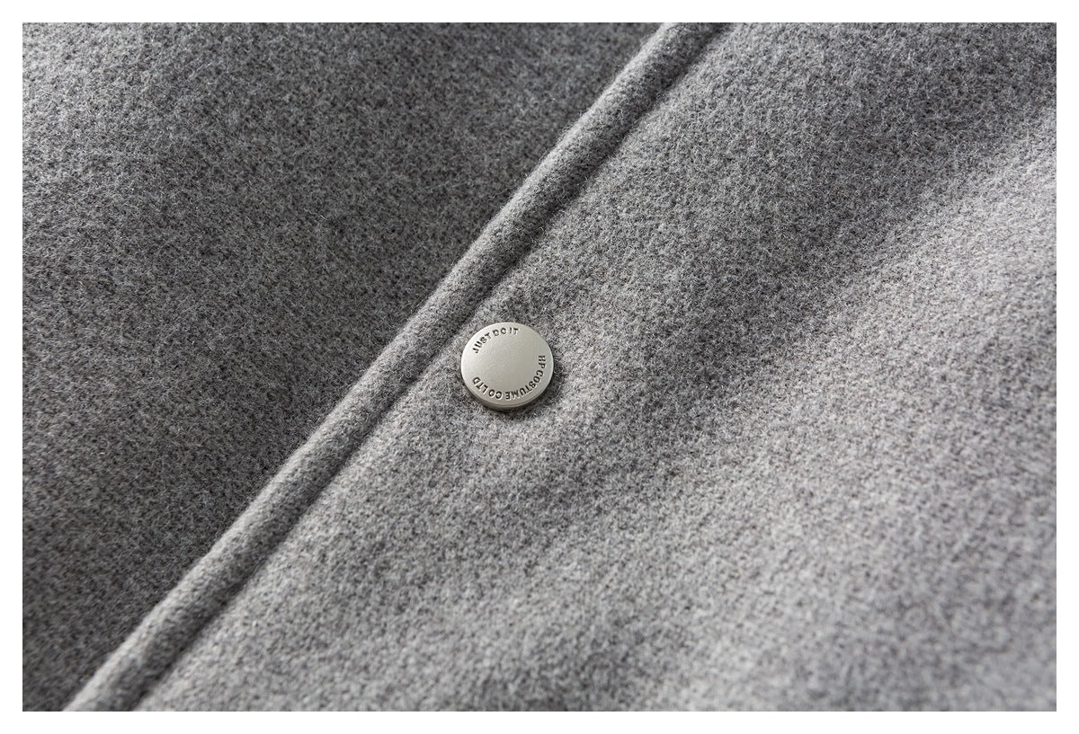 Close-up of a round metal button with English lettering on gray mottled fabric.