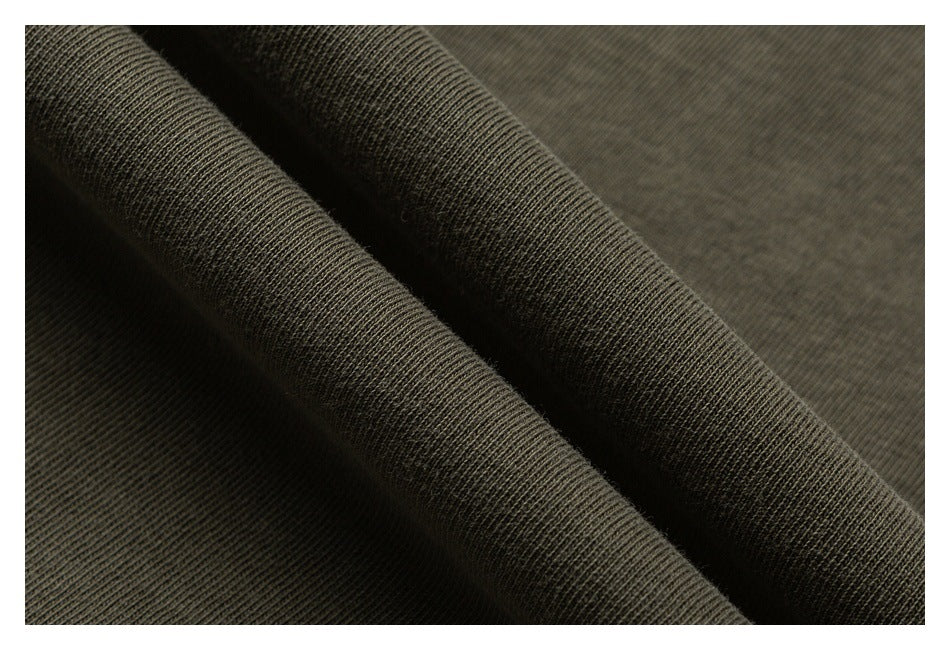 Macro view of olive-gray knit fabric folded to show its ribbed texture.