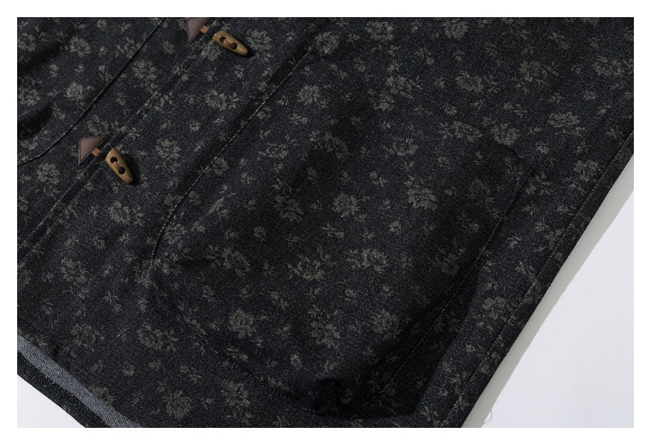 Close-up of a dark floral-patterned jacket front showing wooden toggle fasteners and a large patch pocket.